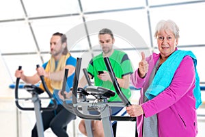 Female senior train with fitness machine and using phone