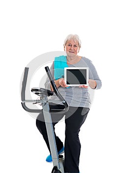 Female senior train with fitness machine and using tablet PC