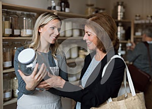 A female shop assistant serving a senior customer in a zero-waste shop.