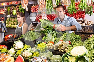 Female shop assistant weighing vegetables on scales photo