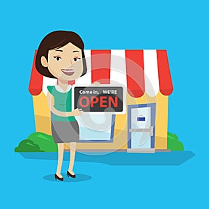 Female shop owner holding open signboard.