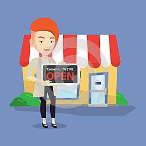 Female shop owner holding open signboard.