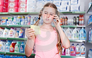 female with shopping list talking on phone