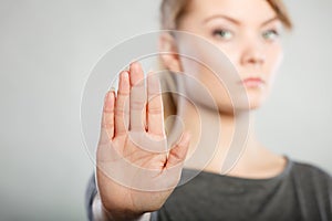 Female shows stop sign by her hand.