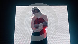 Female silhouette against digital wall. Woman posing on runaway catwalk fashion show in front of digital screen wall