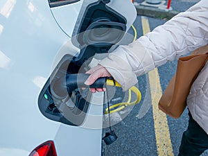 Female silhouette charging a electric car, photo from below