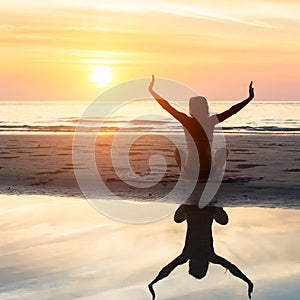 Female silhouette doing yoga exercise at beautiful sunset on the sea beach