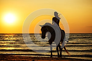 Female silhouette on a horse at sunset by the sea