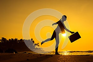 Female Silhouette staying along Ocean Coast with Luggage Bag enjoying scenic View Sea and Sunrise on background. Beach Holiday Co