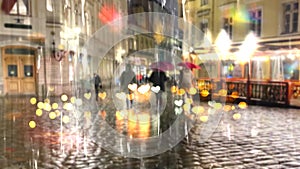 Female silhouette with an umbrella on a road crossing in the evening city in the rain light traffic lights stripes of crossing on