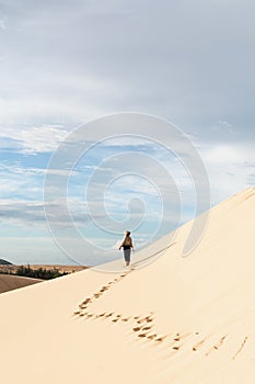 Female silhouette walking in desert sand dunes of Mui Ne, Vietnam