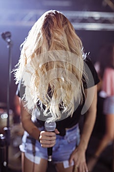 Female singer covering her face with hair while performing at nightclub