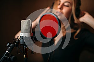 Female singer in headphones against microphone