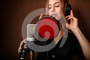 Female singer in headphones against microphone