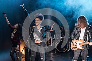 Female singer with microphone and rock and roll band performing hard rock music