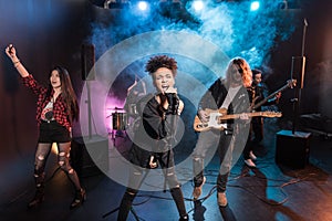 Female singer with microphone and rock and roll band performing hard rock music