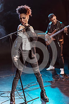 Female singer with microphone and rock and roll band performing hard rock music