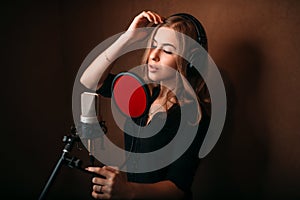 Female singer recording a song in music studio