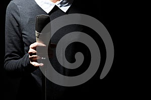 Female singer on the stage holding a microphone on a dark background