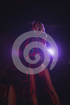 Female singer standing on illuminated stage in nightclub