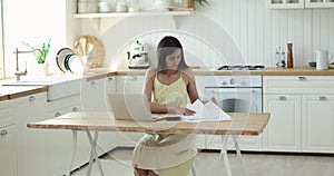 Female sit in home kitchen doing accounting work from home