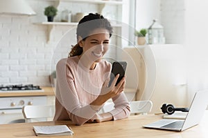 Female sit indoor holding modern smartphone laughing at online video