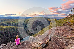 Female sits rock with views over Nepean River and Blue Mountains