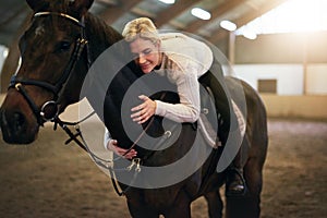 Female sitting astride and hugging black horse