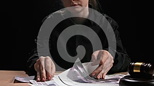 Female sitting at the desk with wooden hammer, dark room bright spotlight. Woman judge silhouette in the court room