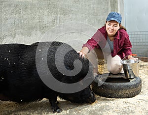 Female sitting and feeding pig