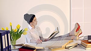Female sitting at her workplace and laughing while reading holding book
