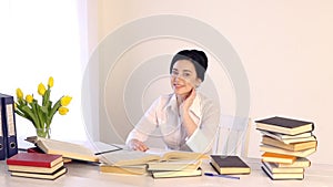 Female sitting at her workplace and laughing while reading holding book