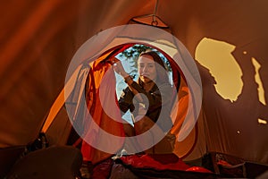 Female is sitting outside of tent entrance