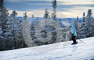 Female skier in blue jacket skiing downhill