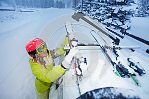Female skier fastening skis to car roof`s rails photo
