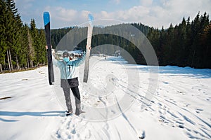 Female skier posing with a pait of skis wearing protective face mask.