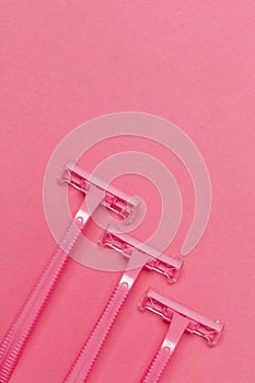 Female Skin Care Concepts. Upper Flat-Lay Image of Three Women`s Colorful Pink Disposable Razors Shavers Placed Reversed Over