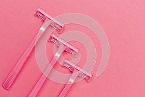 Female Skin Care Concepts. Upper Flat-Lay Image of Three Women`s Colorful Pink Disposable Razors Shavers Placed Reversed Over