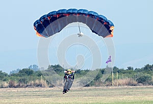 Female skydiver making safe landing on grass with open brightly