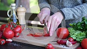 Female slicing tomato for a picnic on wooden cutting board outddors