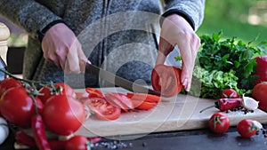 Female slicing tomato for a picnic on wooden cutting board outddors