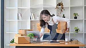 Female small business owner preparing deliveries for clients at her home office.