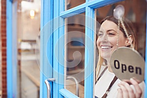 Female Small Business Owner Turning Around Open Sign On Shop Or Store Door