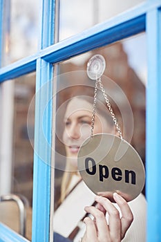 Female Small Business Owner Turning Around Open Sign On Shop Or Store Door