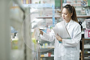 Female pharmacist checking stock inventory in pharmacy.