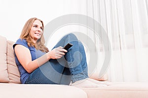 Female smiling relaxing on sofa holding remote control