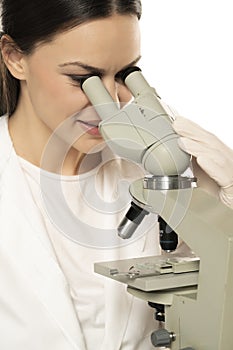 Female smiling scientist looking through a microscope