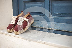 Female sneakers with white laces leaned on the blue door