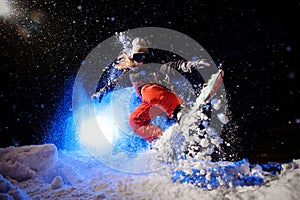 Female snowboarder dressed in a orange sportswear jumping on the mountain slope