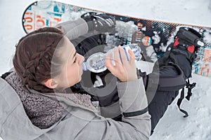 Female snowboarder is drinking for quenching the thirst photo